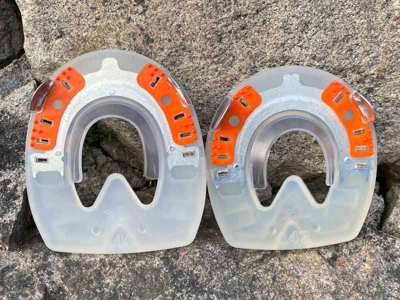 particularly solid and shock-absorbing horseshoes in round and oval shapes stand in front of a stone wall.