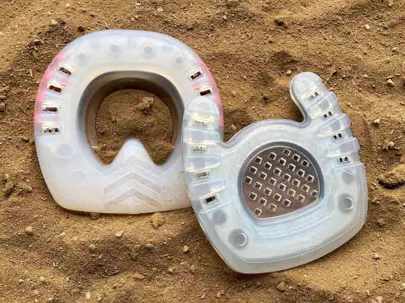 Special models of hoof protection with a straight toe and an open toe are placed in the sand.