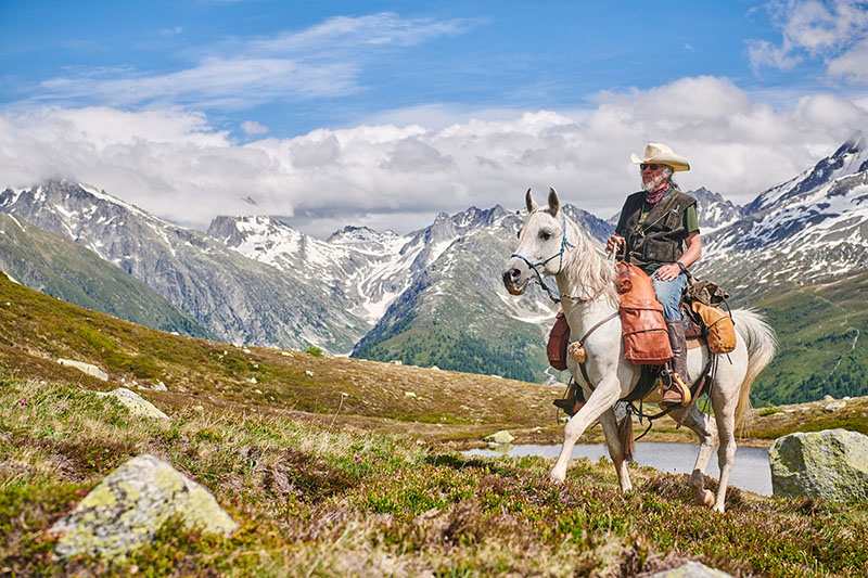 white horse with rider in the mountains