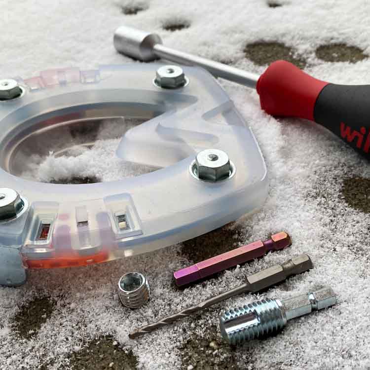 Alternative horseshoes, studs, and tools lying in the snow.