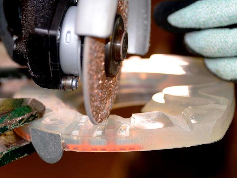 a farrier grinds a profile into the plastic coating of the composite horseshoe using an angle grinder