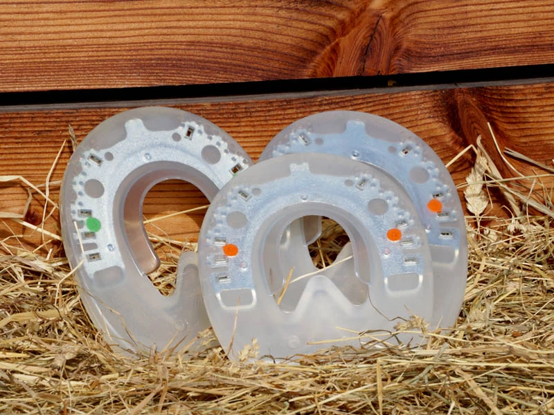 Different versions of the Duplo Nailless plastic horseshoe for glue-on use: shown with green and orange dots indicating plastic hardness.