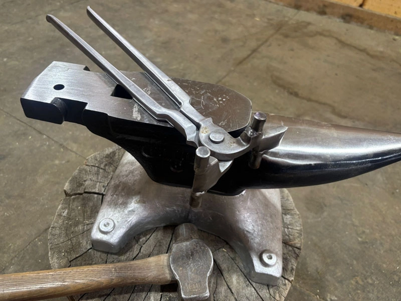 The CL shoe spreader designed by Caro Lucas is lying on an anvil next to a forging hammer.