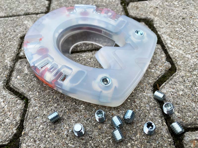 horseshoe made of plastic with a metal core and stud holes lies next to metal closure plugs on gray stones