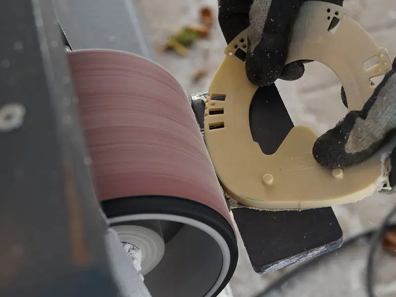 Fitting a horseshoe with a wedge pad to the hoof shape using a belt grinder