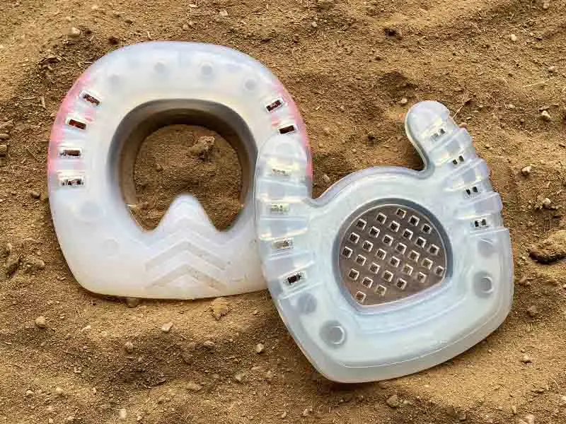 Special models of hoof protection with a straight toe and an open toe are placed in the sand.