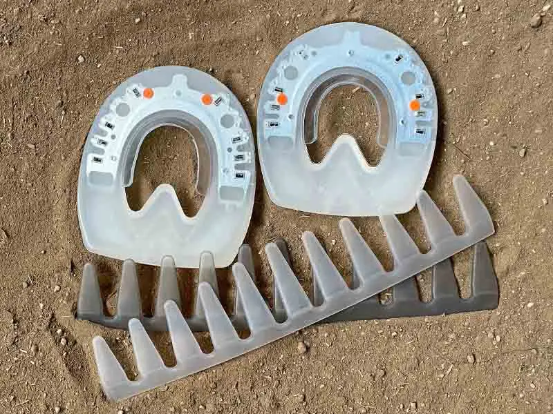 The urethane shoes for glued application and glue-on collars Easy and Pro are placed in the sand of the riding arena.