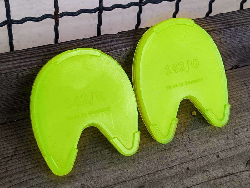 A round and an oval hoof sole protector for clicking into the opening in the plastic horseshoe stand side by side.