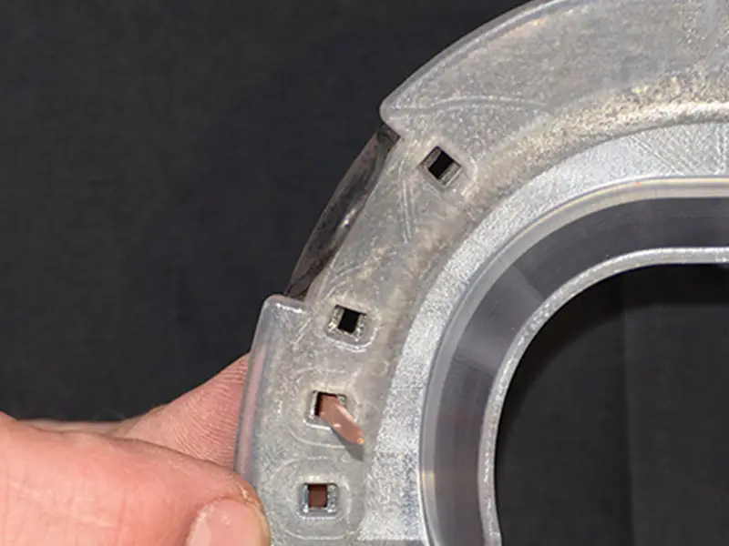 The farrier demonstrates that the nailing slots in the 'KC' hoof pad align precisely with the Comfort horseshoe model by Kerckhaert by passing a nail through one of the holes.