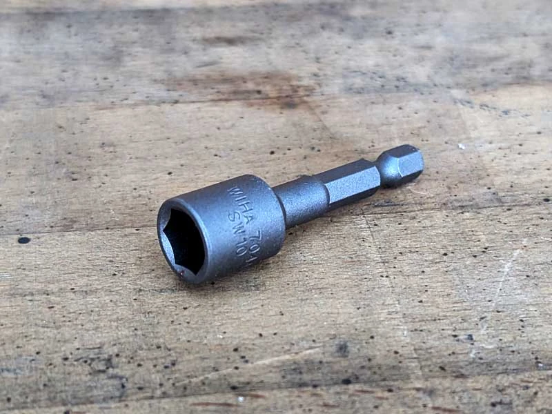Un embout de clé à crampons est posé sur un établi.