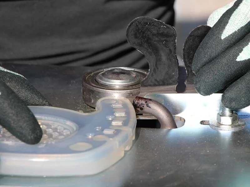 herrador suelda una herradura de pinza abierta con una lengüeta adhesiva utilizando un dispositivo especial