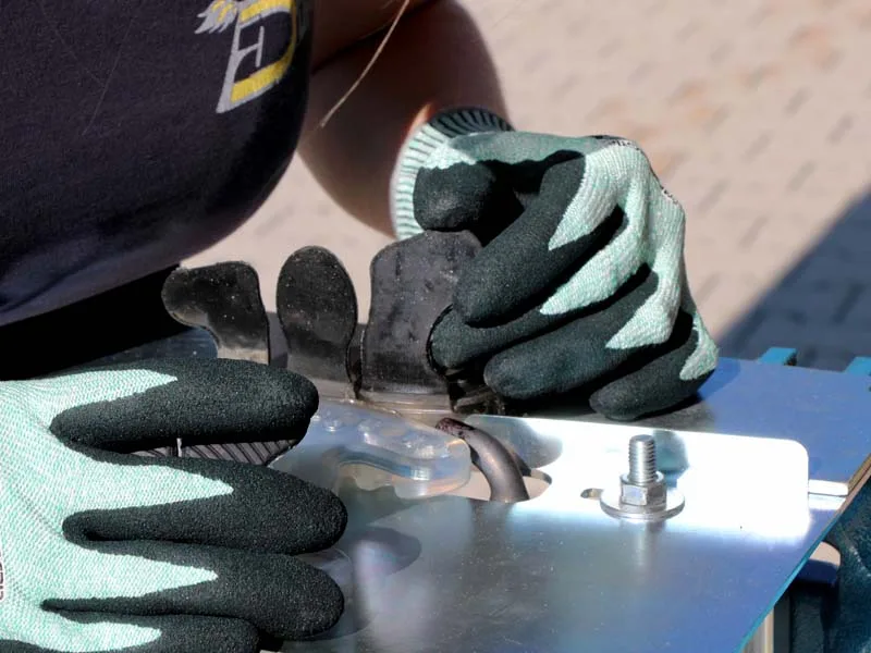 Una herradora suelda una herradura de pinza abierta con una lengüeta adhesiva, lleva guantes y utiliza un dispositivo especial