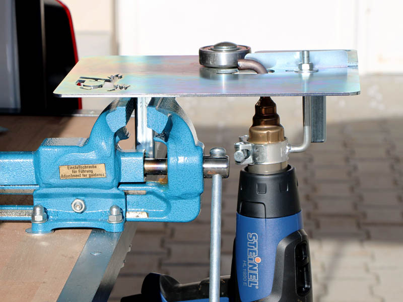 welding device for glue-on horseshoes is clamped in a blue vise.